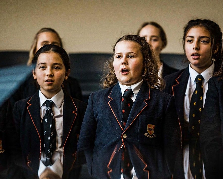 Children in school uniform singing as part of a school choir