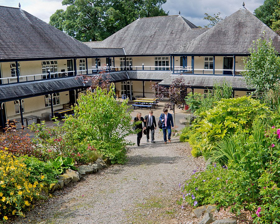 Students walking through a landscaped courtyard between boarding houses.