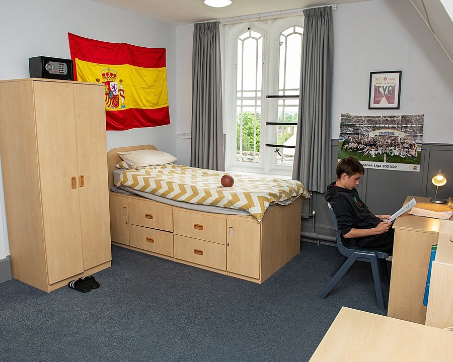 Boarding school dormitory room with single bed, desk, storage and study space