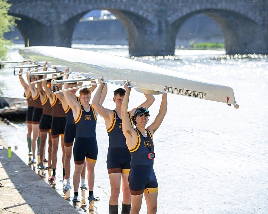 Haberdashers’ Monmouth rowing team carrying a boat by the River Wye