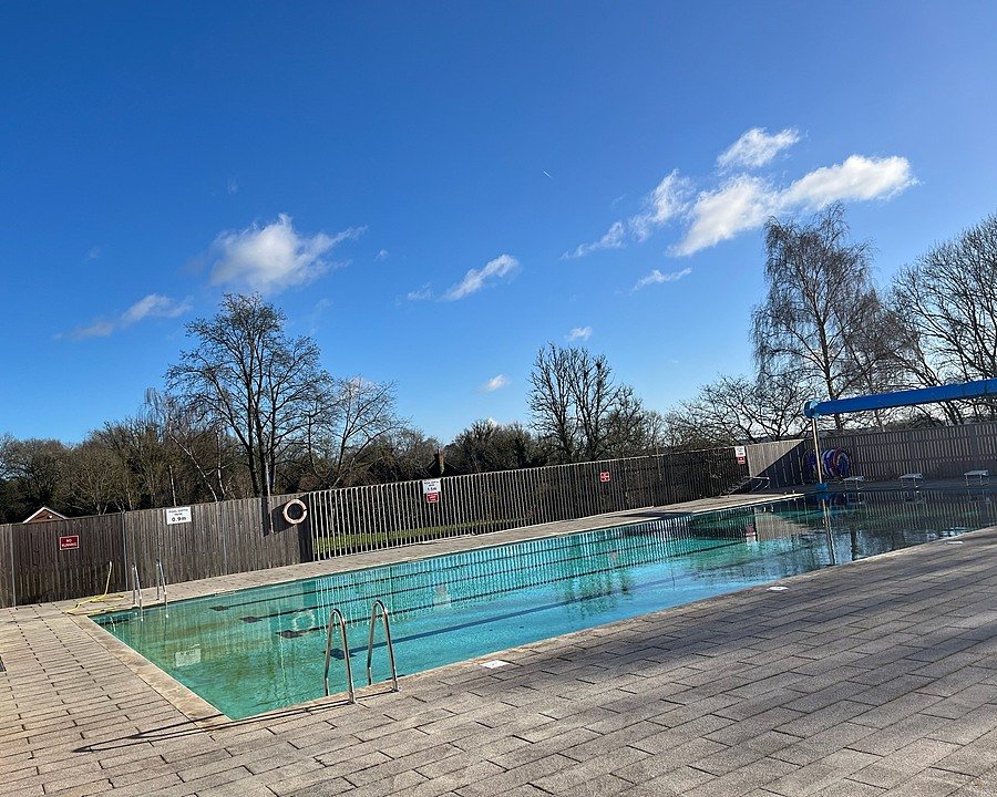 Outdoor swimming pool with surrounding fence and trees