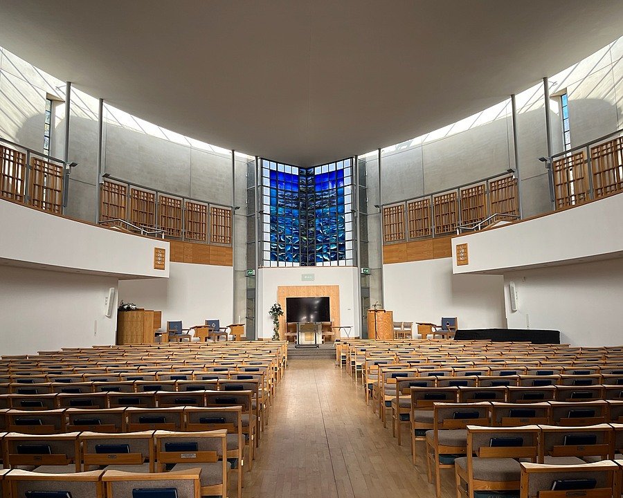 Interior of a chapel with rows of seating and stained glass window