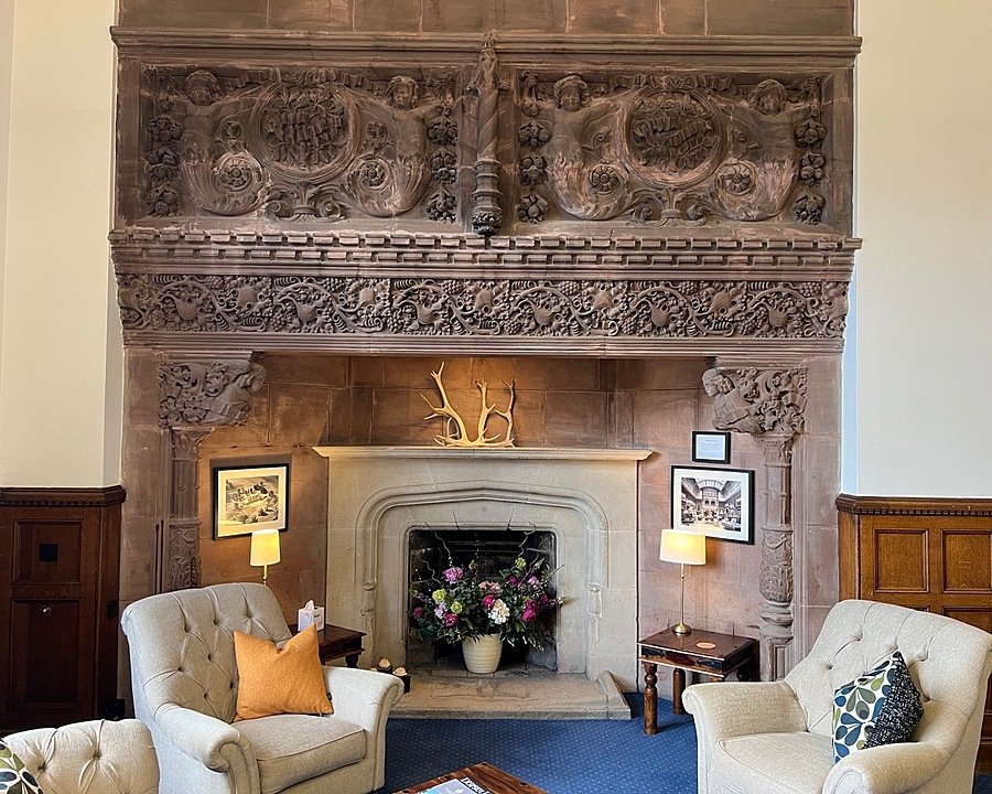 Two cosy armchairs in front of an impressive fireplace made of stone