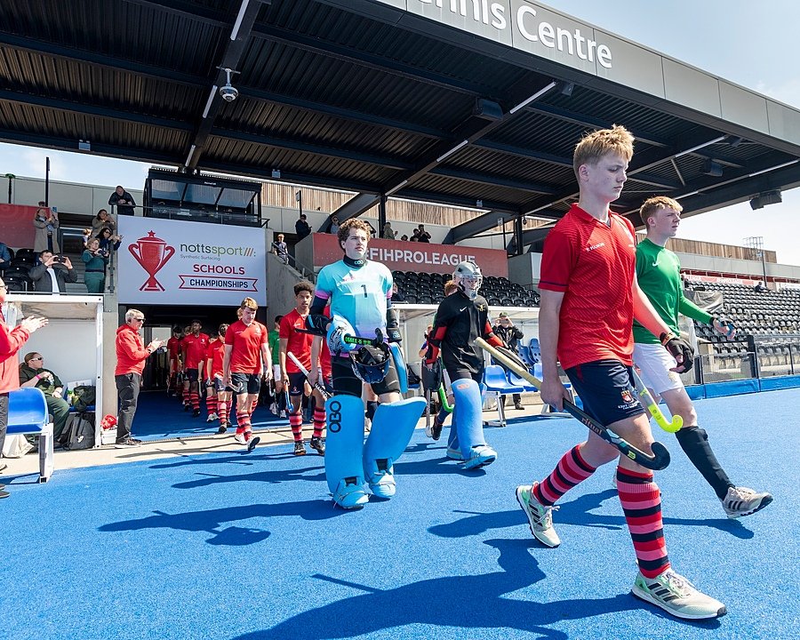 A hockey team is entering their hockey pitch for a match