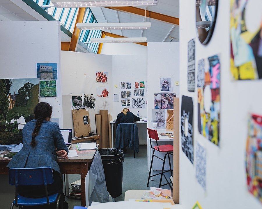 two students working at their desks in the school's bright art department
