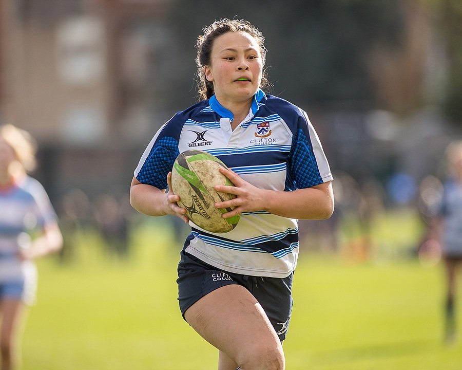 A female student at Clifton College running with a Rugby ball
