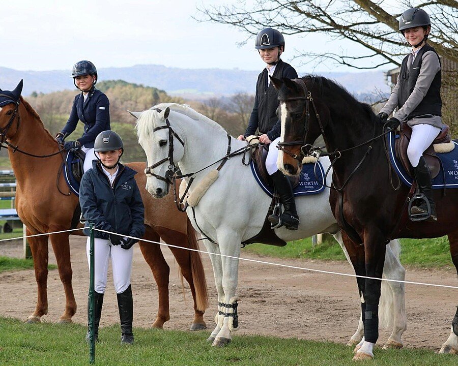 The Equestrian Team at Worth School with three happy students on their horses