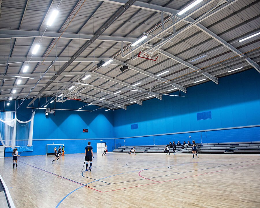 Modern, well-lit indoor hockey hall with pupils in training