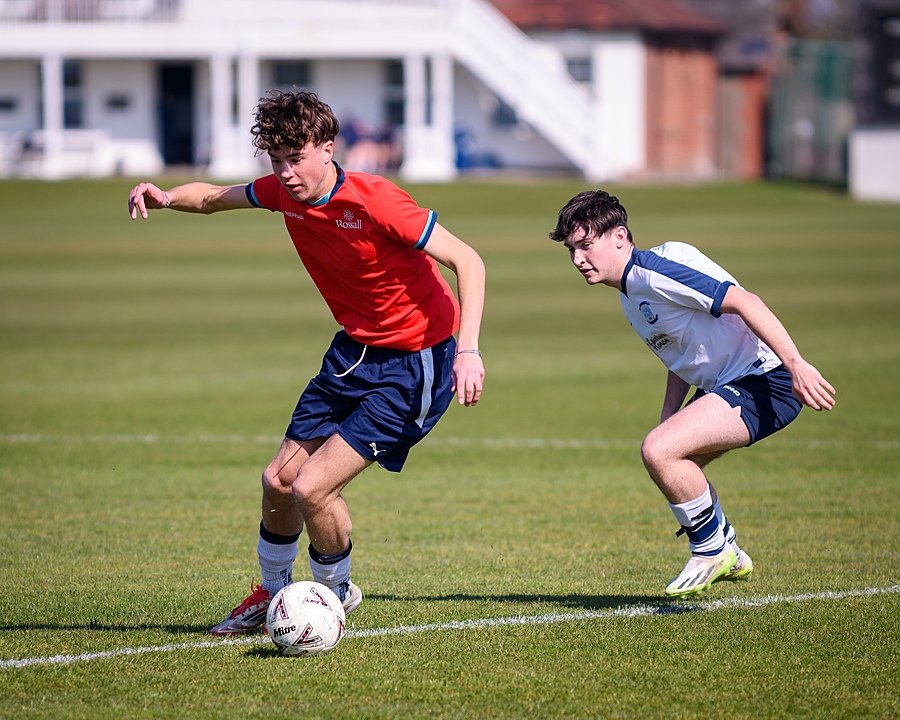 two opposing football players in their jerseys on the pitch in a game