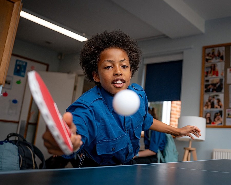 Student playing table tennis indoors at Pangbourne College