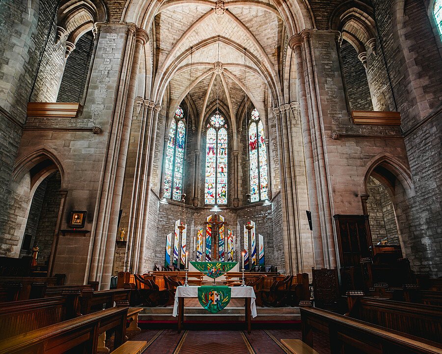 An impressive grey-brick chapel from the inside with an altar lit by candles