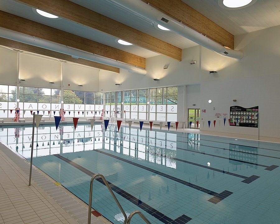 An indoor swimming pool with lane markers and natural light coming through large windows.