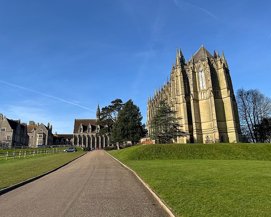 A grand chapel and school buildings under a clear blue sky, viewed from a paved path.