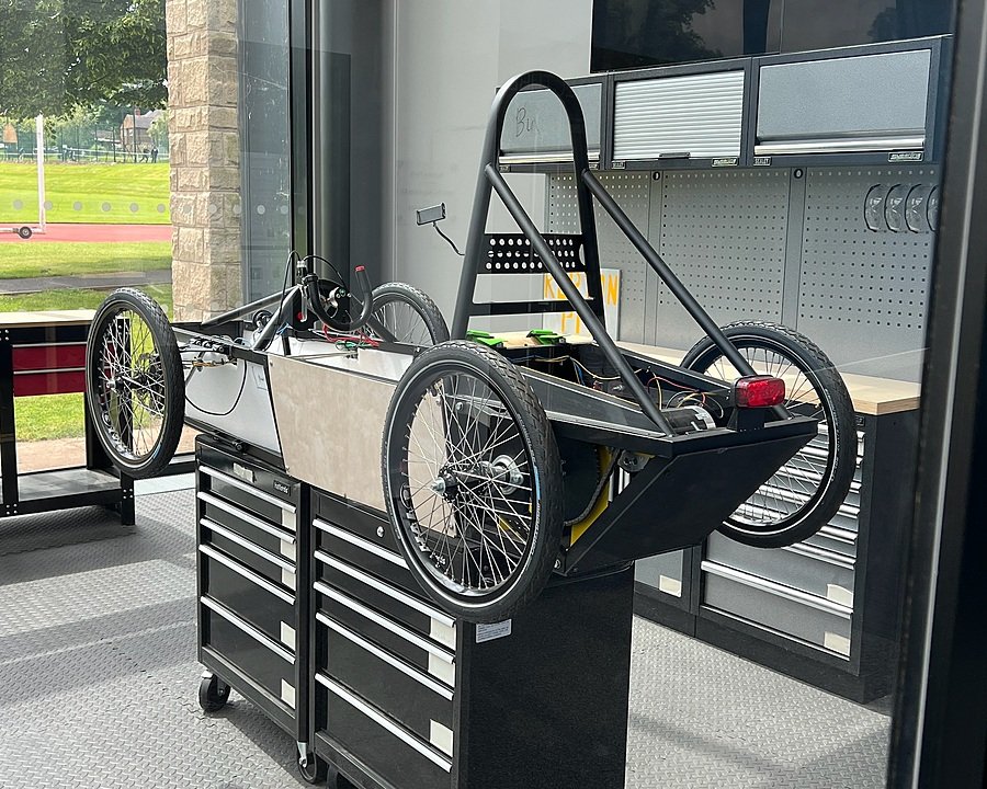 A pupil-built green race car, perched on two tool cabinets