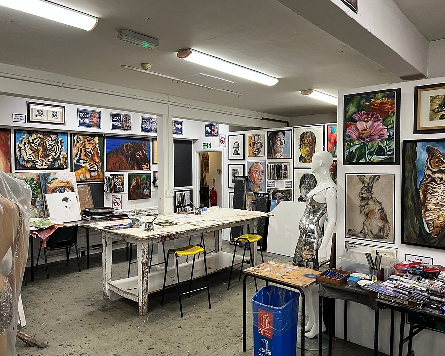 Art classroom filled with colourful student paintings, mannequins, and art materials spread across work tables.