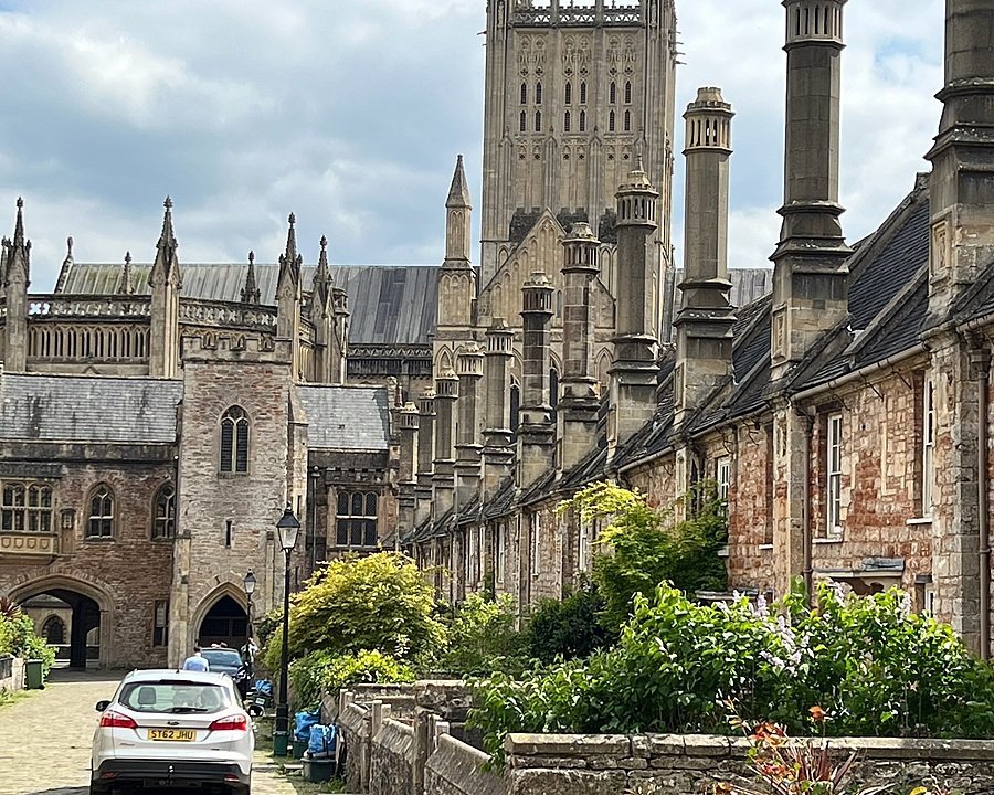 Row of old stone houses leading to a grand cathedral with towers and detailed Gothic architecture.