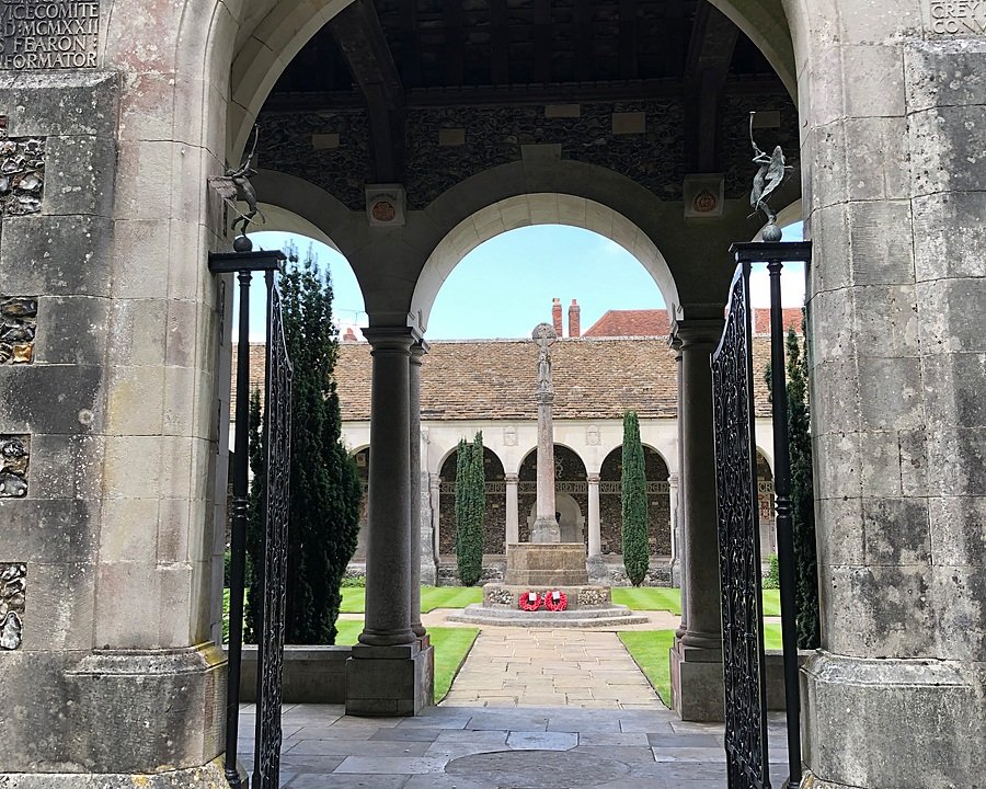 A stone gate with a courtyard and lawn in the background