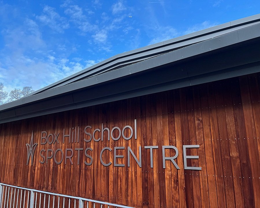 A wood-cladded building with letters saying Sports Center on it