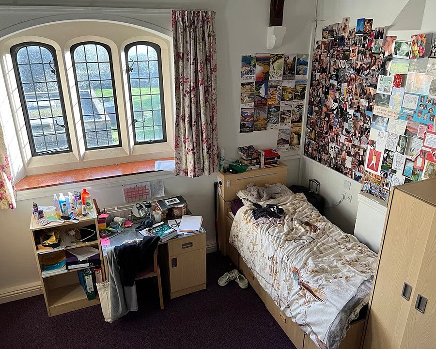 A single room in a boarding house with beautiful old windows overlooking the campus