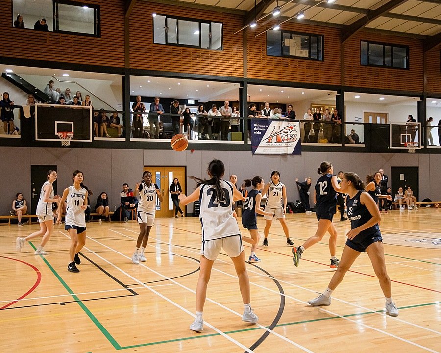 Girls in the middle of a basketball game in a sports hall