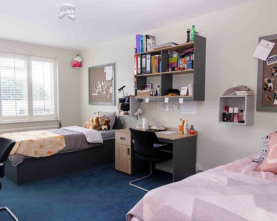 A bright room with two beds and a desk