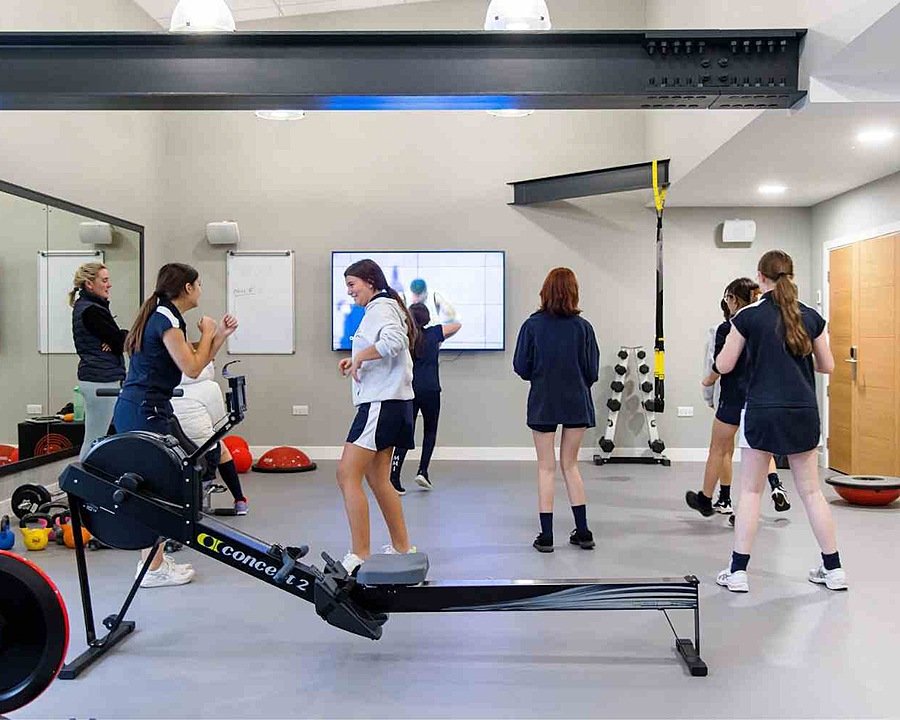 A fitness room with rowing maching, weights and other equipment with girls training