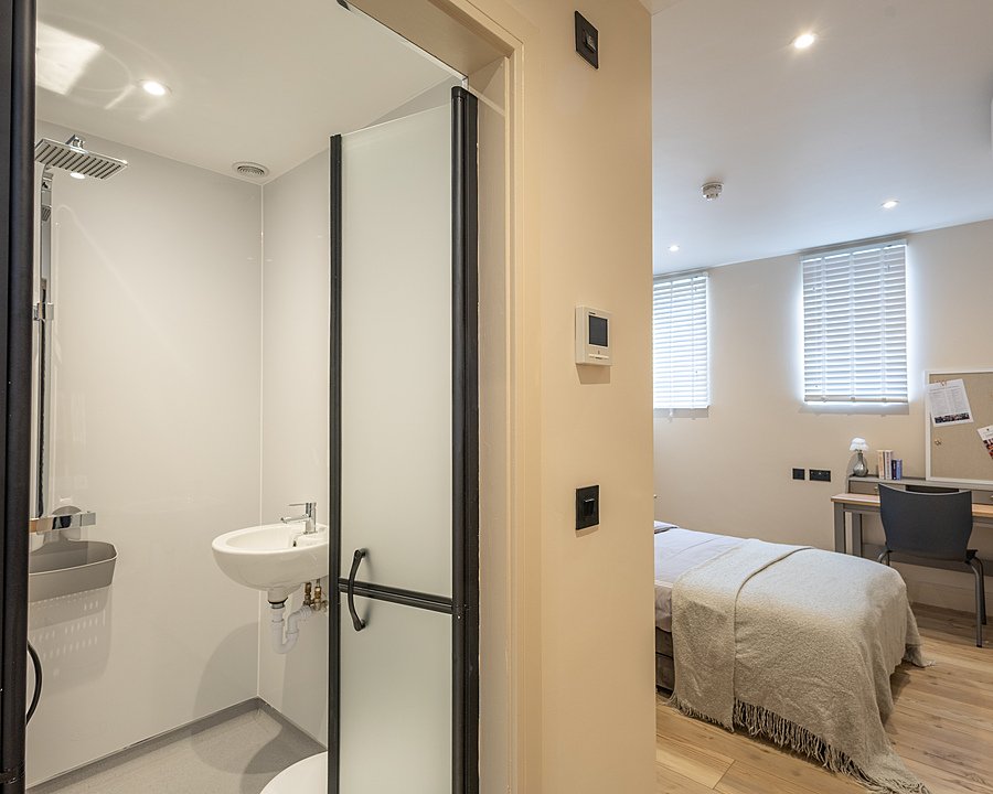 Modern boarding house bedroom with en-suite bathroom, shower, bed and desk in a bright student room.