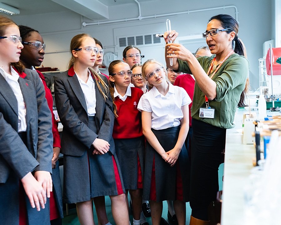 Teacher explaining a science experiment to a group of students in a classroom.