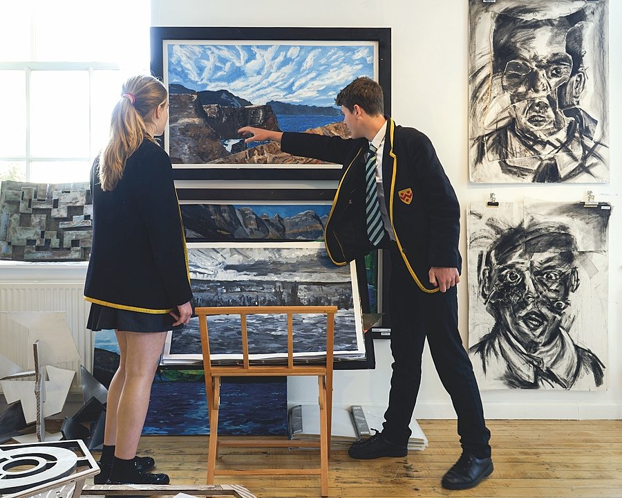 A boy pointing at something in a painting whilst girl looks on