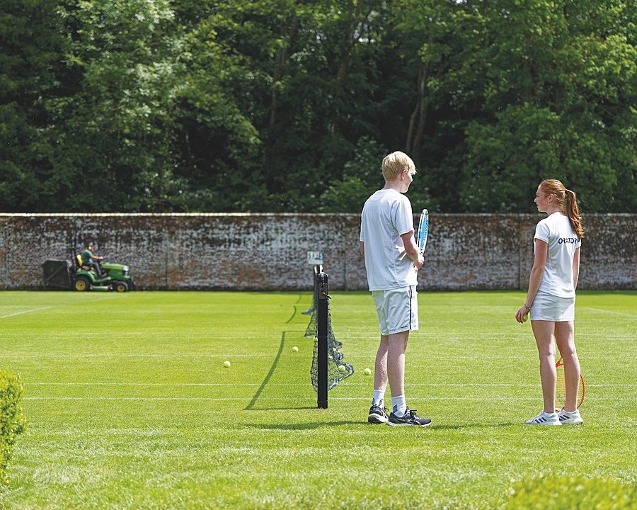 Boy and girl on a lawn tennis court on a sunny day