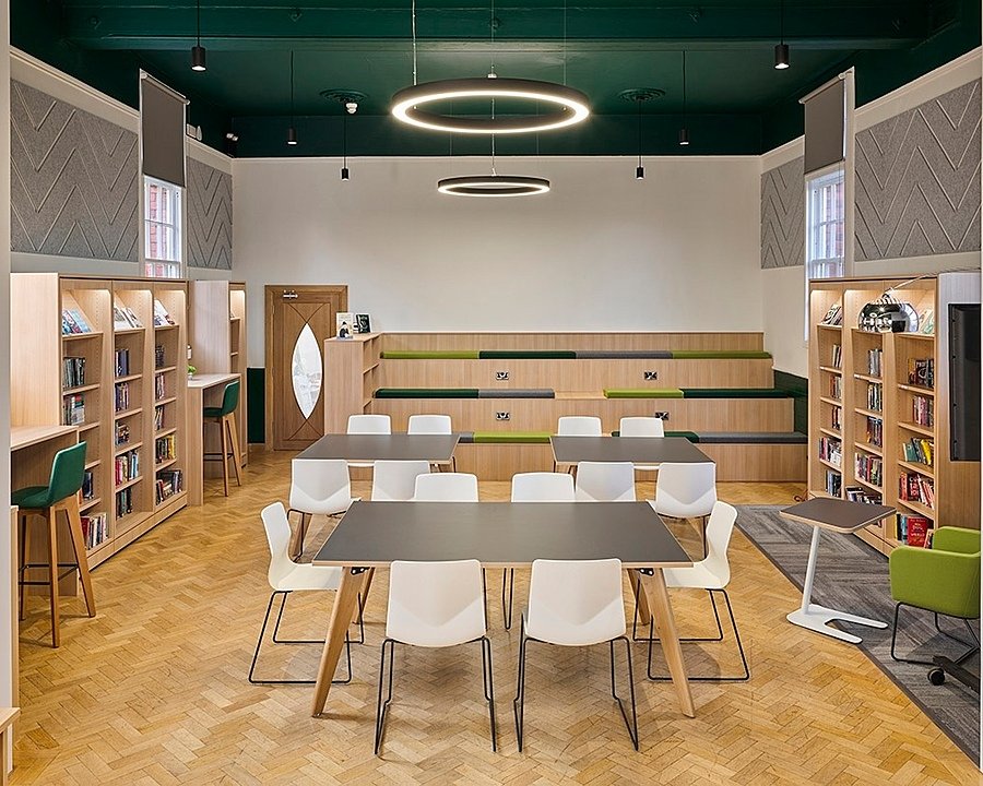 A modern classroom with wooden floors, modern table and chairs and bookshelves