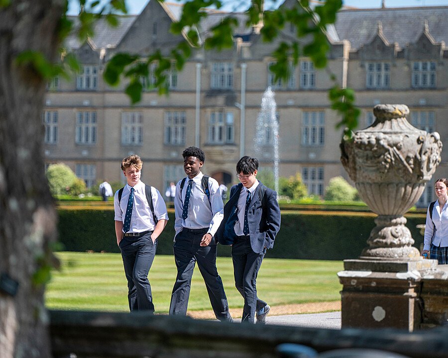 pupils in their uniforms walking over the Canford School campus with a water fountain in the background