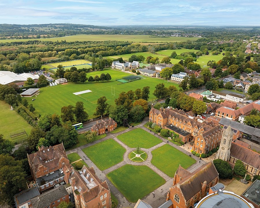 Aerial view of an expansive school campus with sports fields, academic buildings, and tree-lined paths.