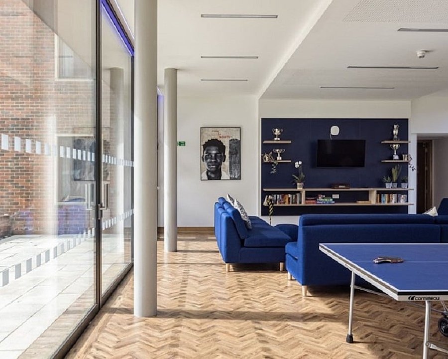 Well-lit room with table tennis table and blue sofas