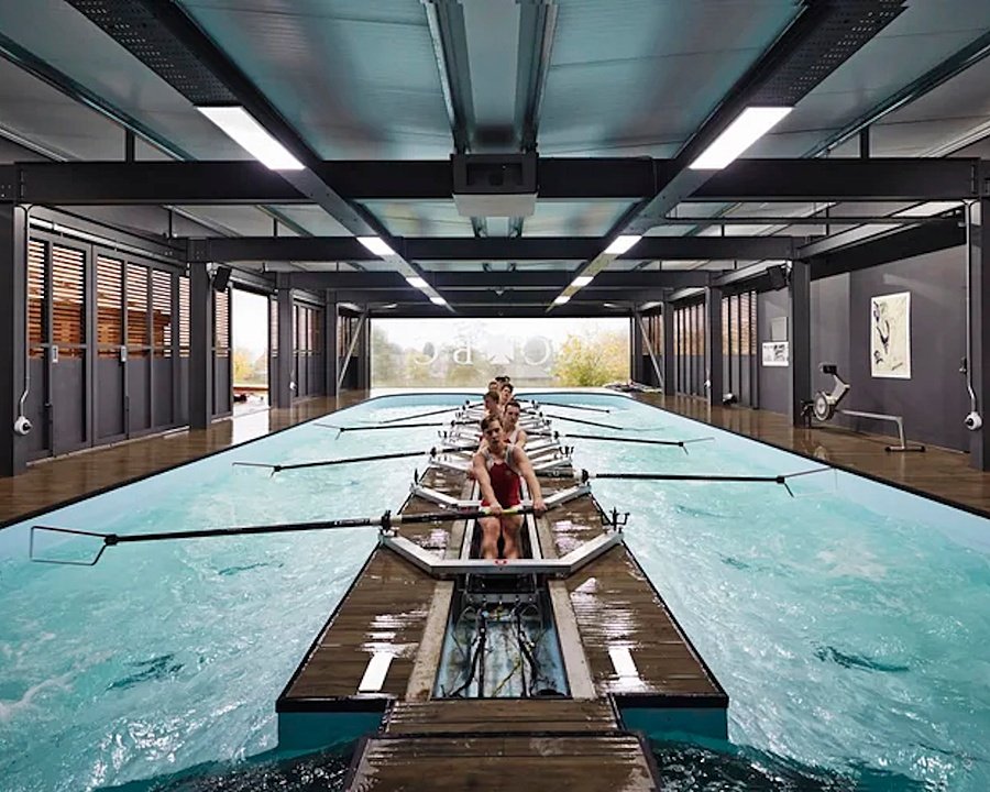 Modern building with a huge water tank and boys with oars at rowing practice