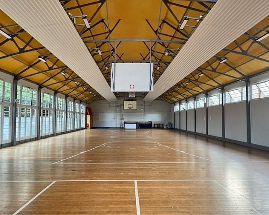 Modern sports hall with side of glass windowed walls and a basketball hoop