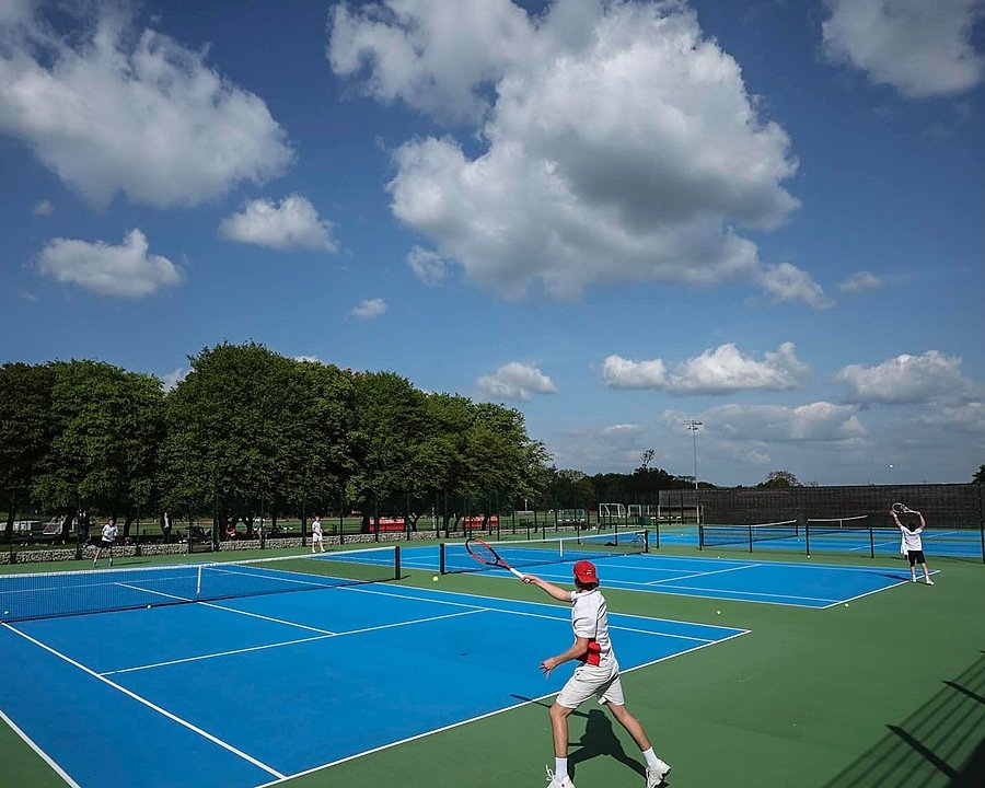 Tennis courts with boys playing tennis in good weather