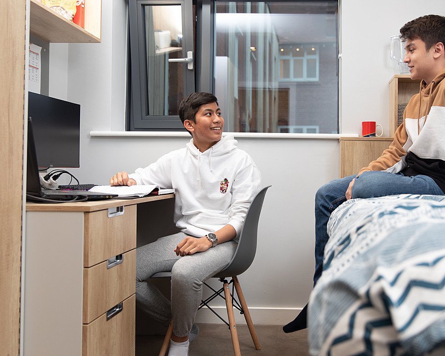 Two boys having a chat in a modern boarding house bedroom