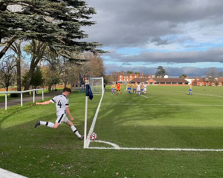 A footballer is taking a corner on the green