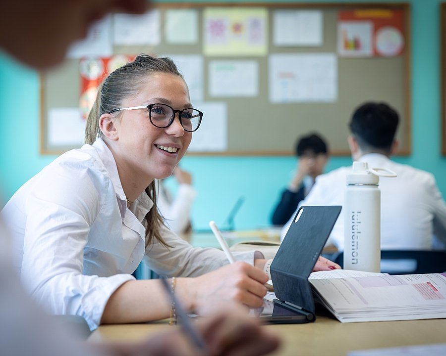Student studying with laptop in a British boarding school classroom.
