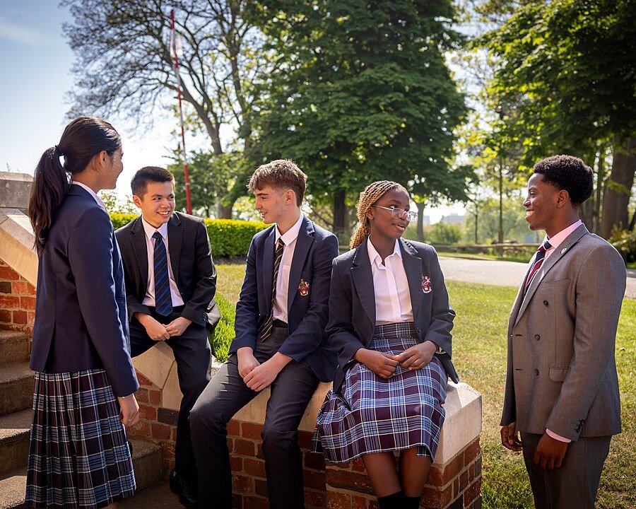 Students in uniform relaxing on a UK boarding school campus.
