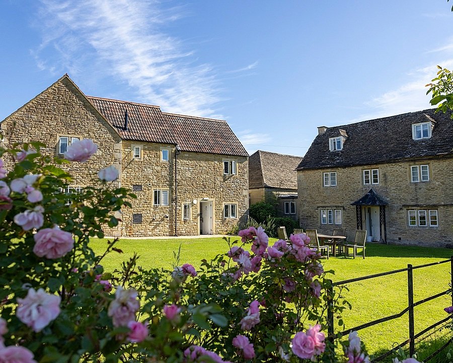 the pretty school buildings out of field stones with pretty pink rose bushes in the foreground