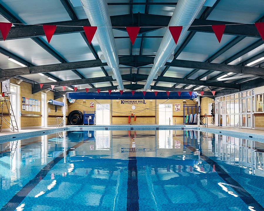 Indoor swimming pool with blue tiles and red triangular flags hanging from the ceiling.