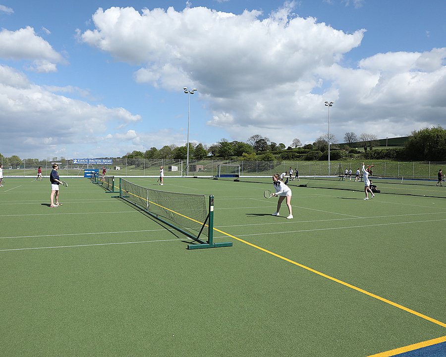 Pupils playing tennis on an outdoor-court in good weather