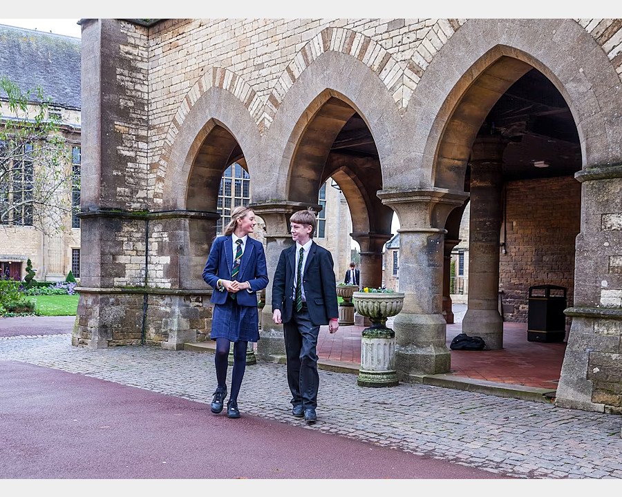 Two pupils walking along old buildings of Uppingham School