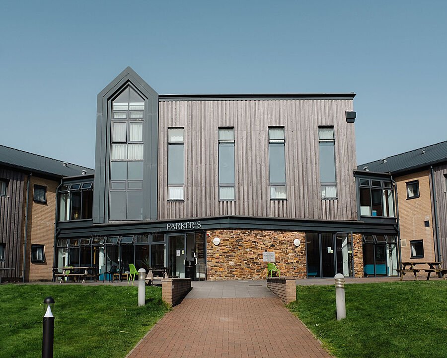 Modern boarding house with dark wood panelled walls, long windows and tower like staircase
