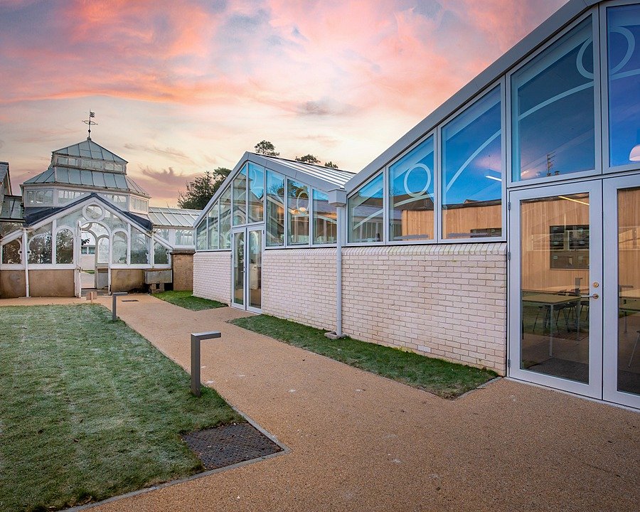Modern school buildings with glass façades, walkways and green areas on campus.