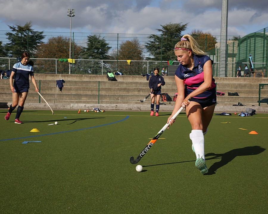 Girl playing hockey in training with other girls in the background