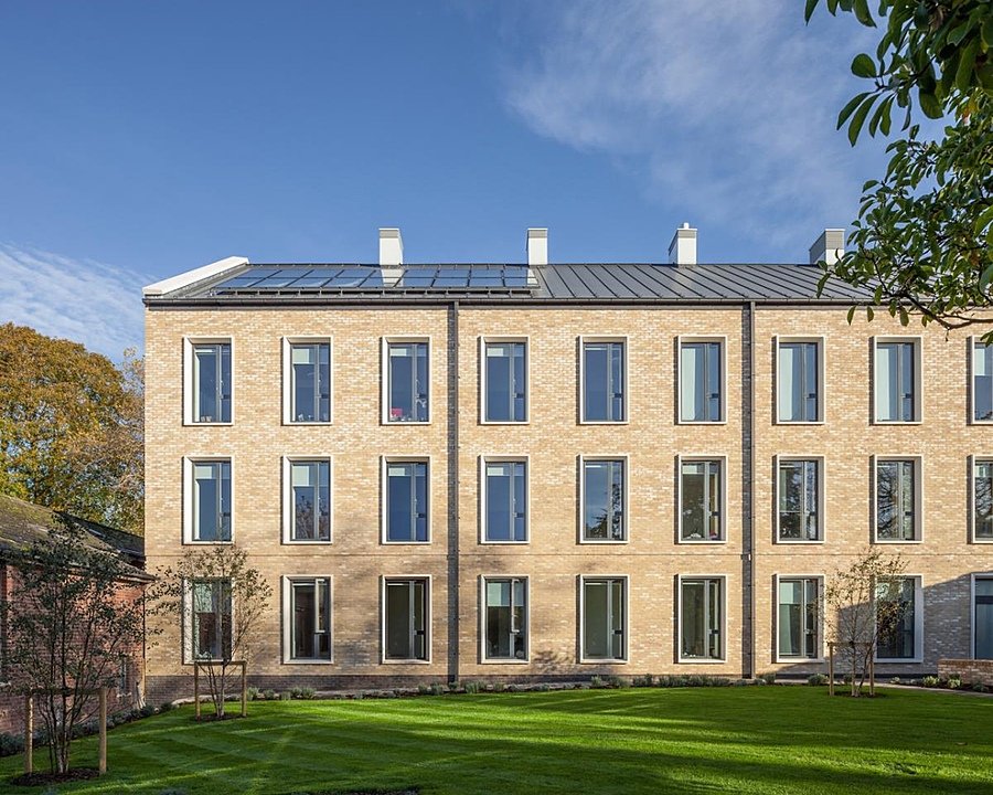 A modern, yellow-brick boarding house with large windows