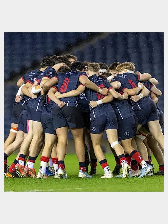 Boys in rugby clothes in a huddle having a team conversation